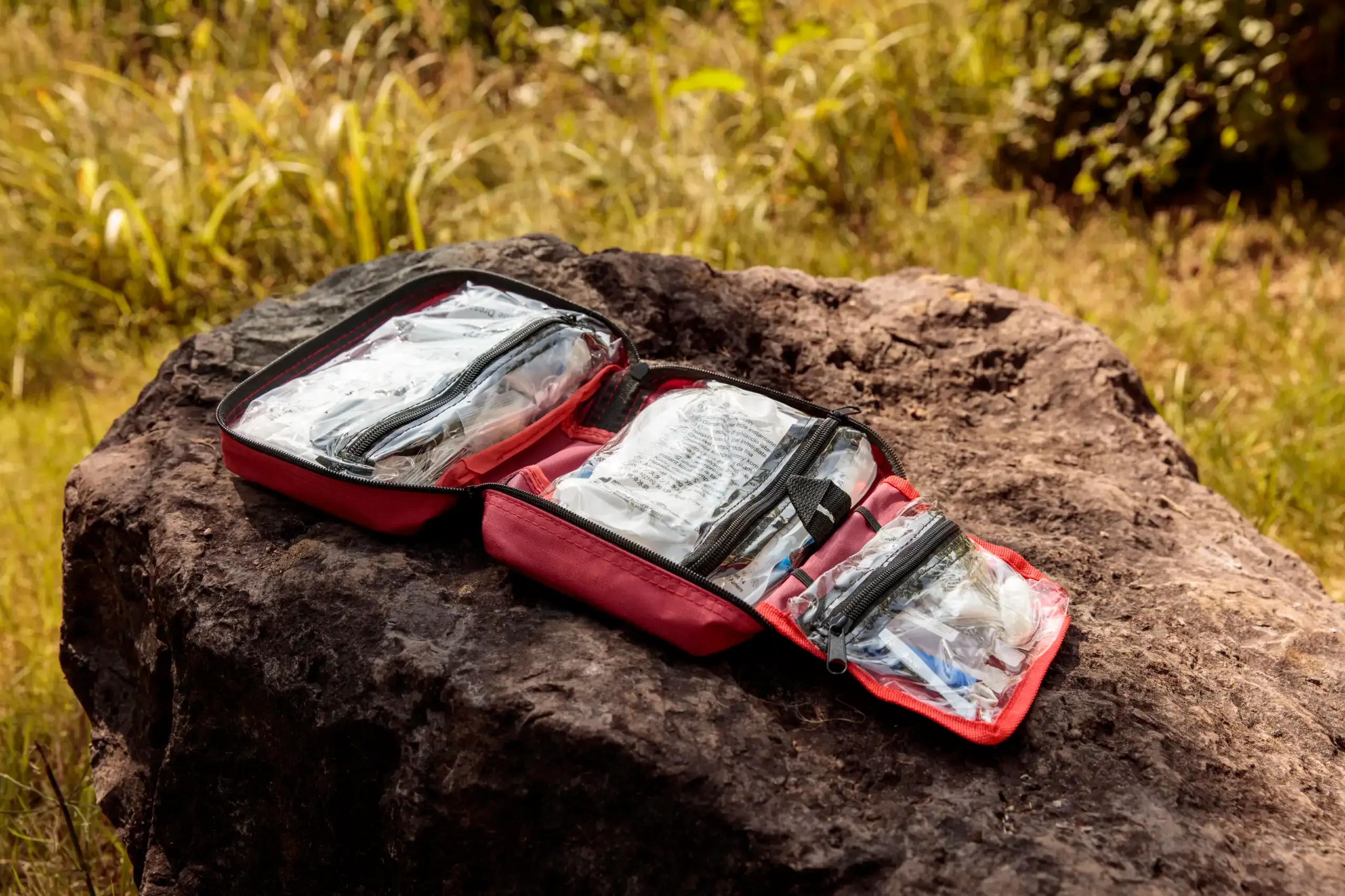 compacte rode ehbo set geopend op rots met verbandmiddelen en noodmateriaal