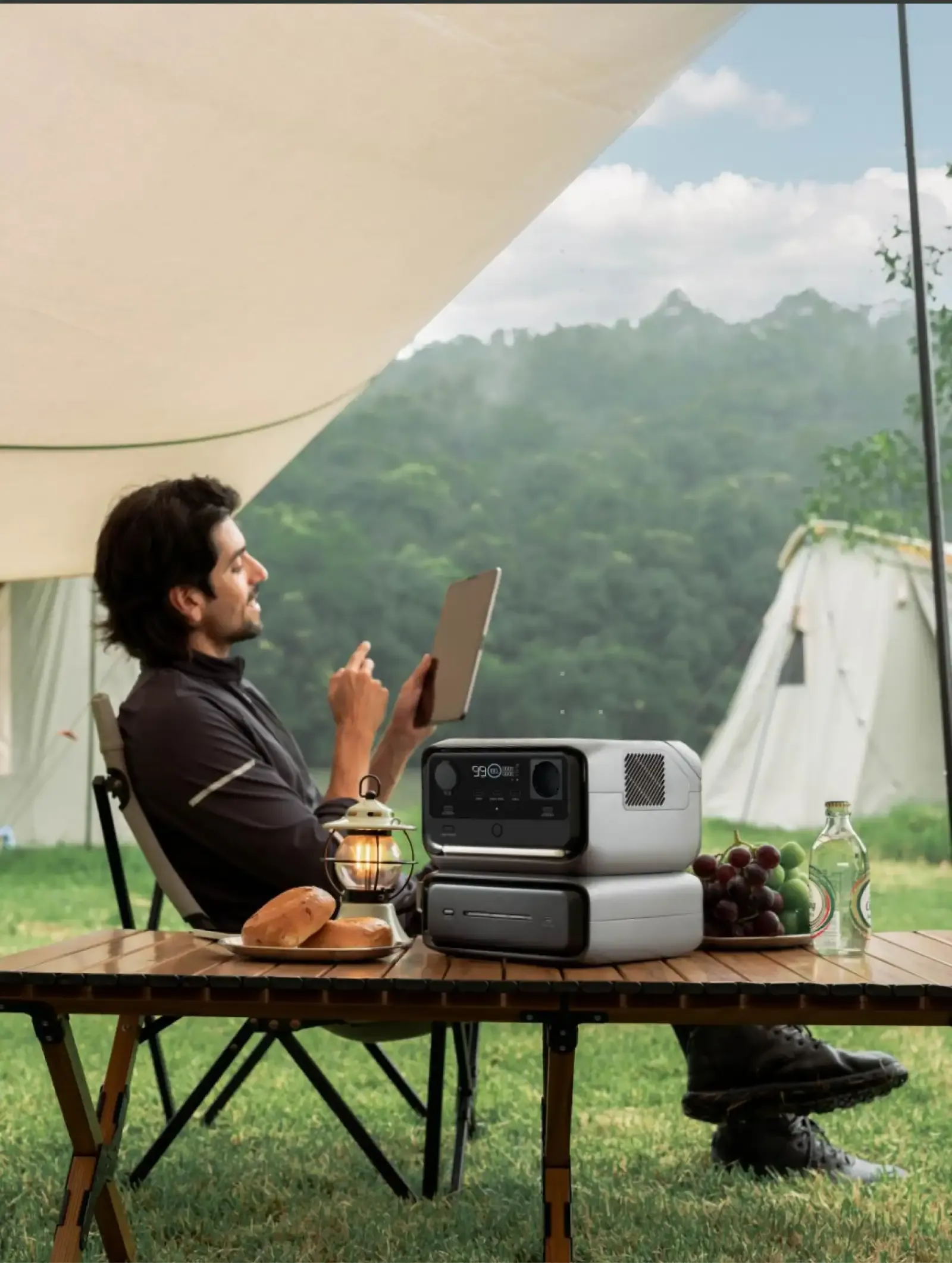 man gebruikt tablet op camping met ecoflow powerstation en extra batterij