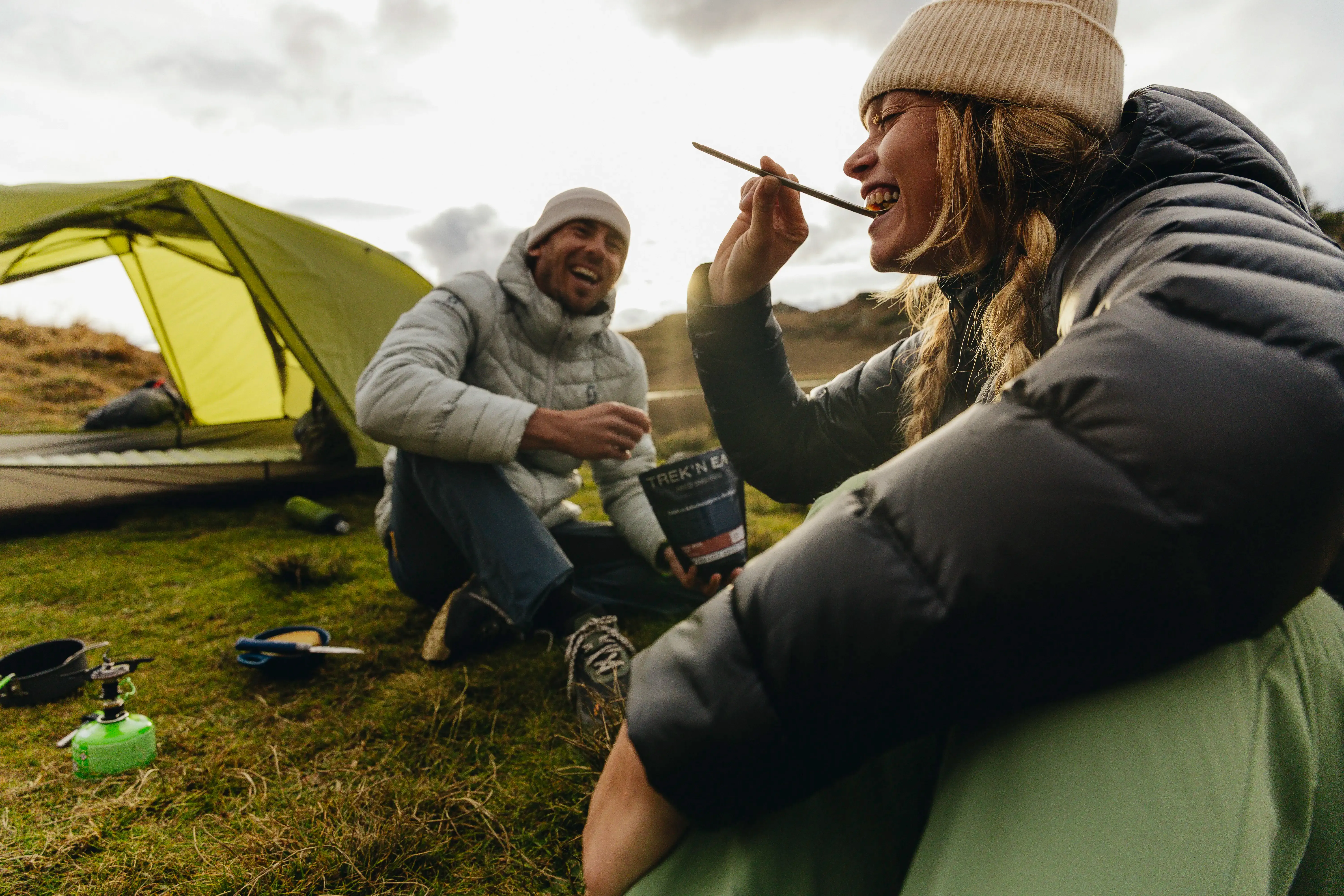 twee kampeerders eten trek n eat vriesdroogmaaltijd bij tent met campingbrander