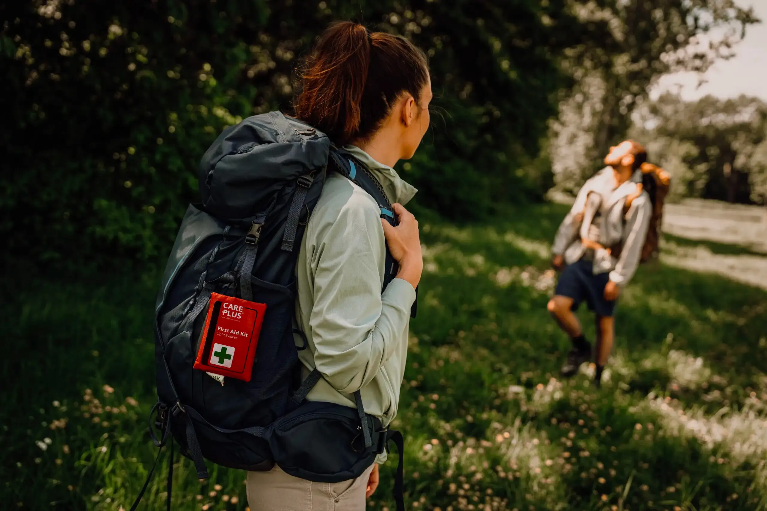 wandelaarster met care plus ehbo set aan rugzak op wandelpad